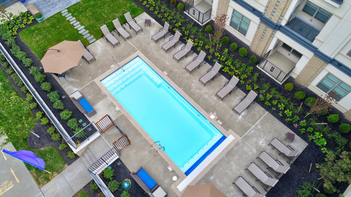 Aerial view of a residential swimming pool with surrounding lounge chairs and landscaped areas.