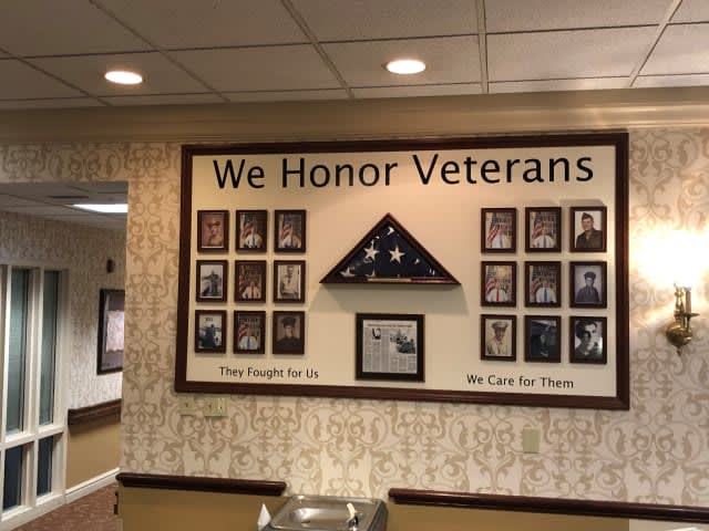 A wall display honoring veterans with framed photos and a folded American flag.