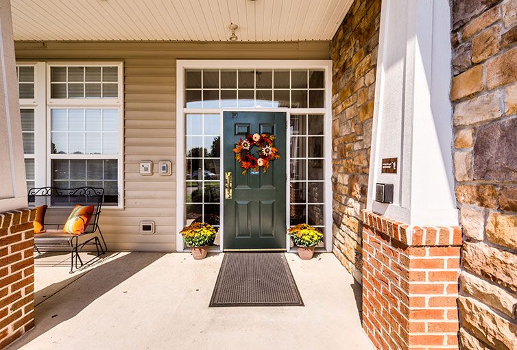 A welcoming entrance decorated with an autumn-themed wreath and potted plants.