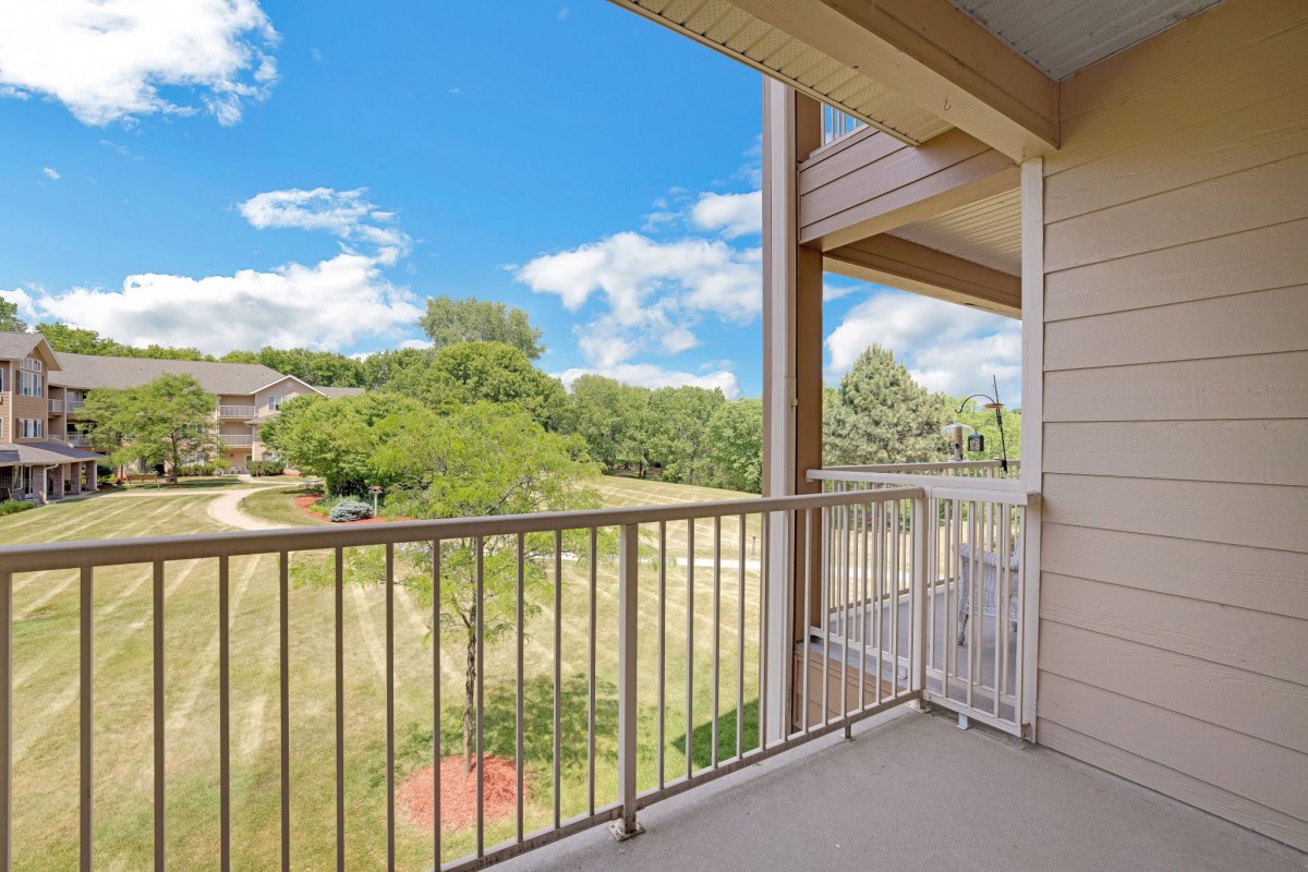 A balcony with a view of trees under a clear blue sky.