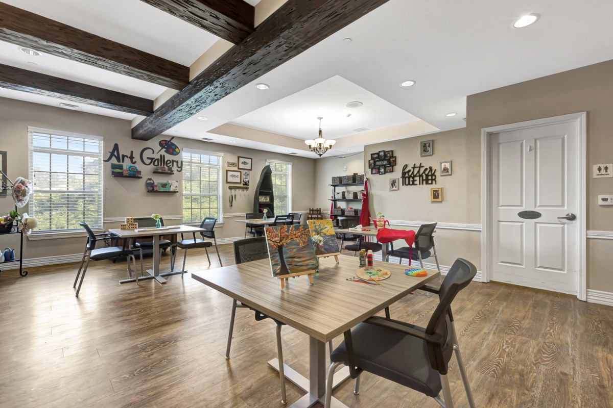 A well-lit art classroom with tables, chairs, and creative wall decorations.