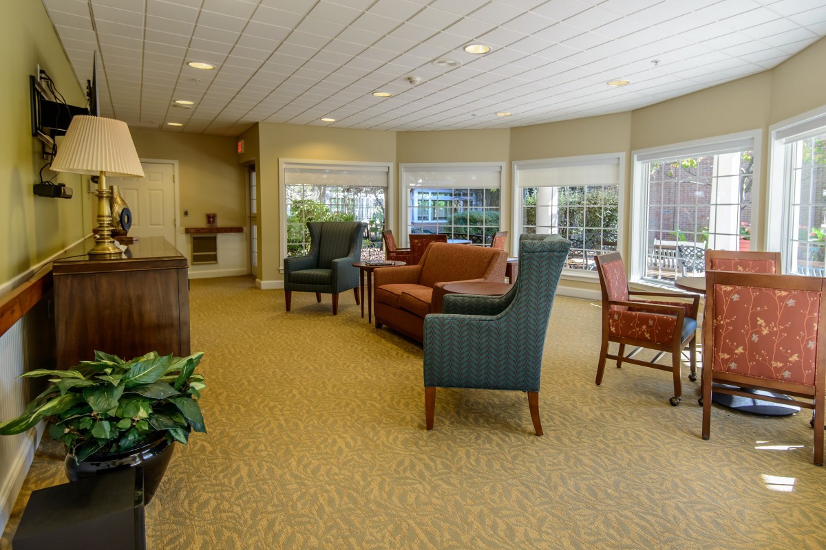 A comfortable living room with sofas and chairs, featuring large windows for natural light.