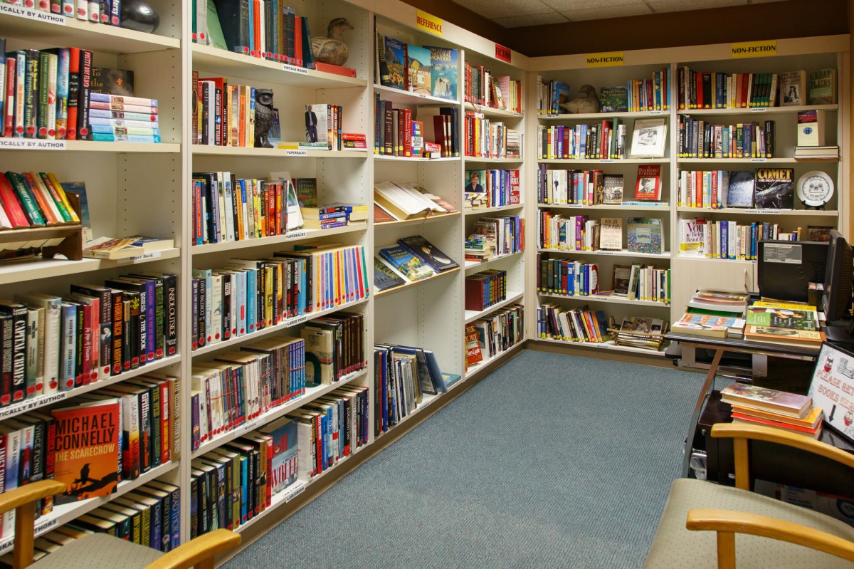 A cozy corner of a library filled with books on white shelves.