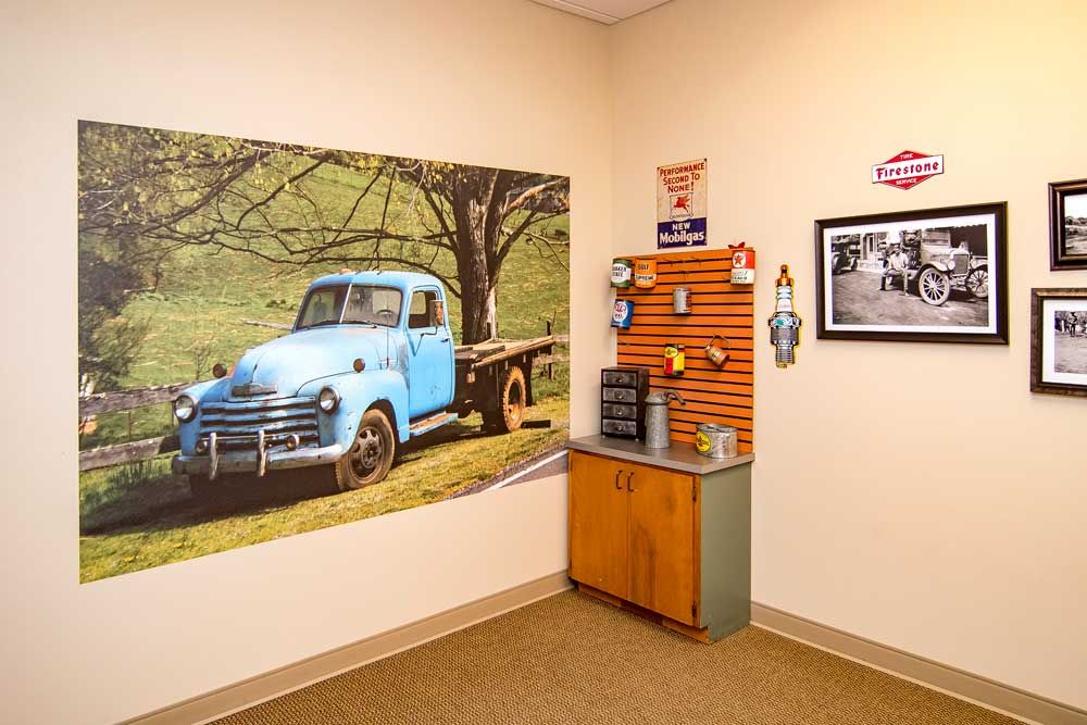 A cozy office corner featuring a large vintage truck wall mural, a coffee station, and nostalgic decor elements.