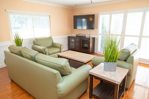 A cozy living room featuring green sofas, a coffee table, and a TV against a light-colored wall.