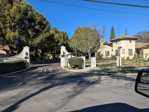 A serene residential entrance with gates bordered by lush greenery under a clear blue sky.