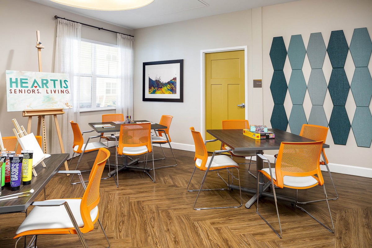 A modern dining area with orange chairs and glass tables, featuring contemporary decor and bright accents.