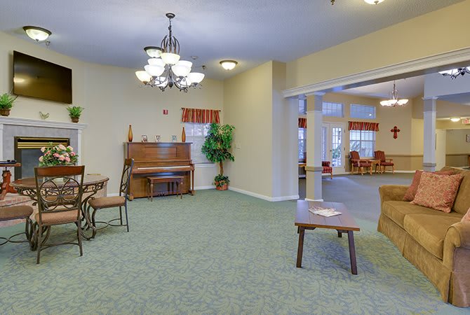 A cozy living room featuring a piano, chandelier, and comfortable seating.