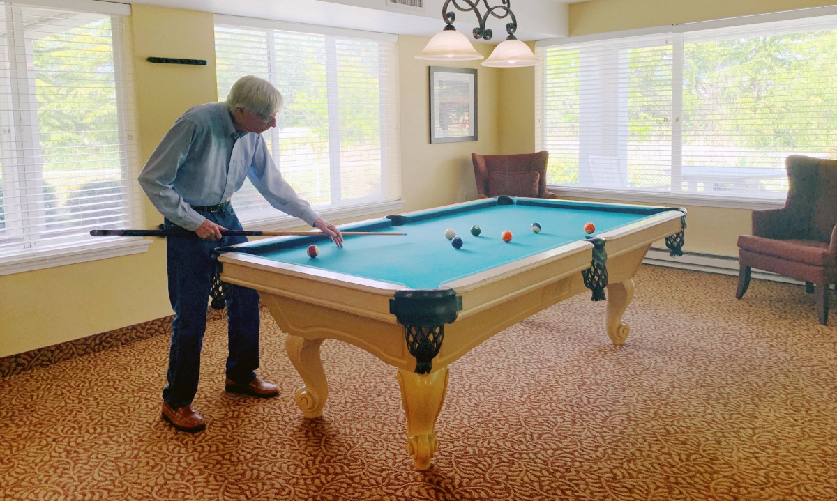 A person playing billiards on a pool table in a well-lit room.