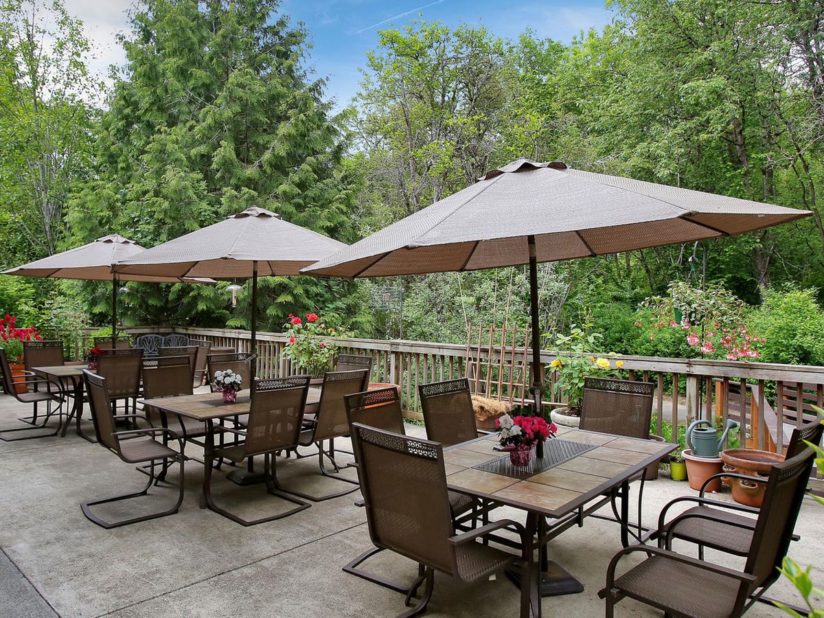 A peaceful outdoor patio with tables and umbrellas surrounded by lush greenery.