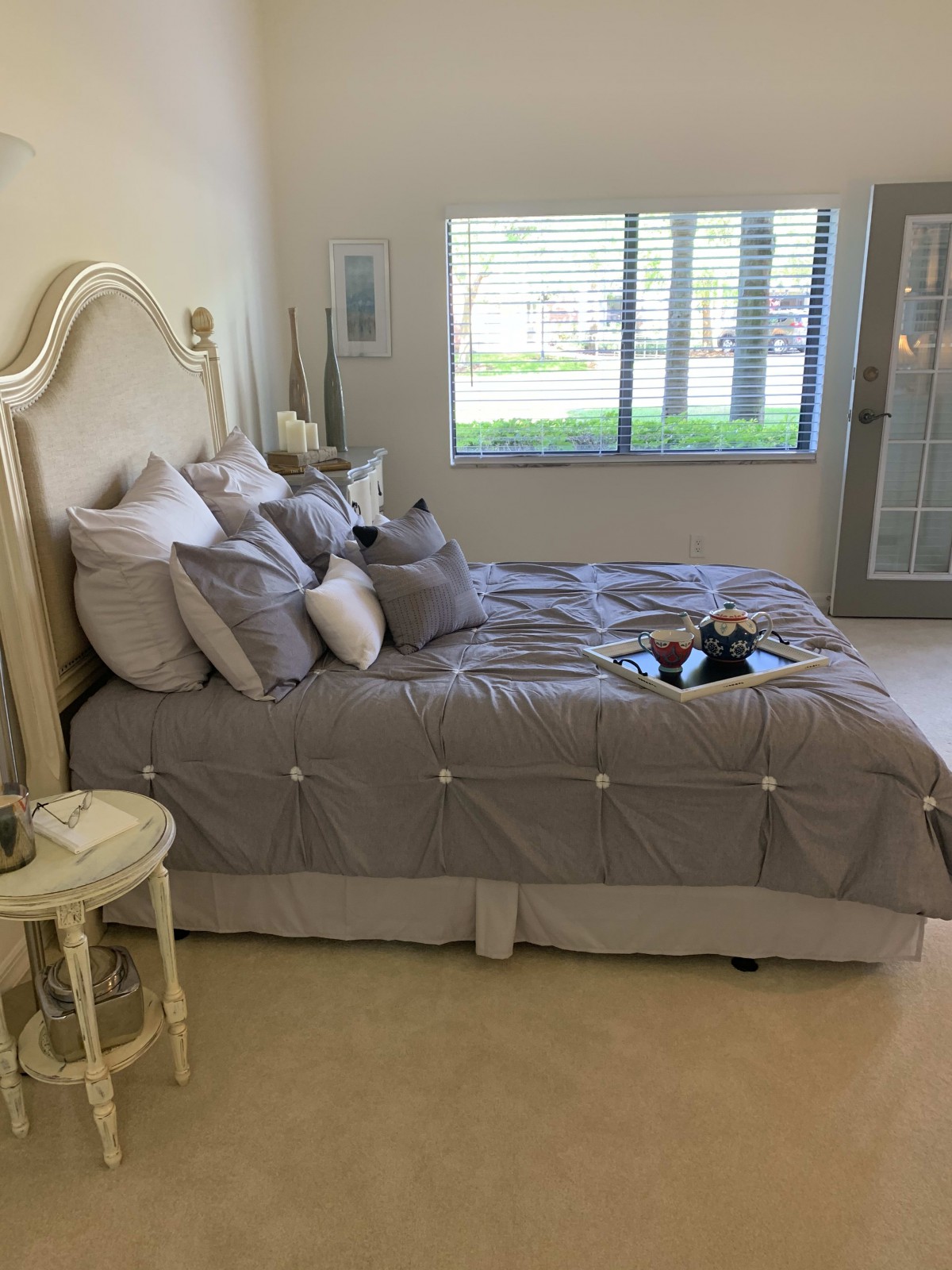 A cozy bedroom with a neatly made bed, soft pillows, and a side table by the window.