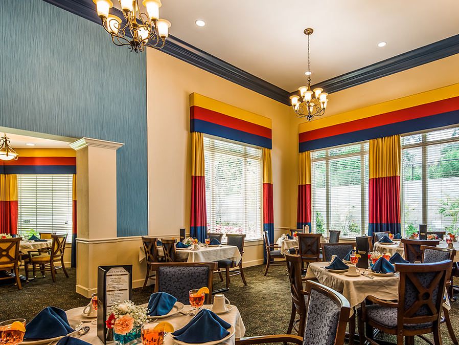 An elegantly decorated dining room with neatly set tables and colorful curtains.