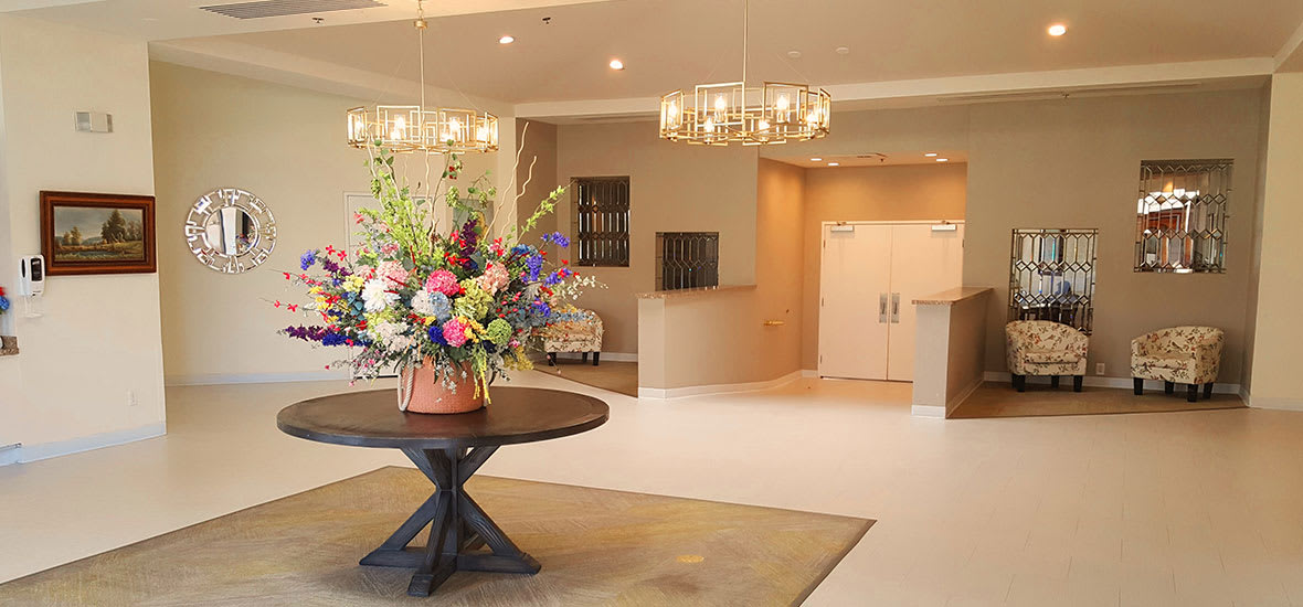 A modern lobby featuring a central floral arrangement and elegant chandeliers.