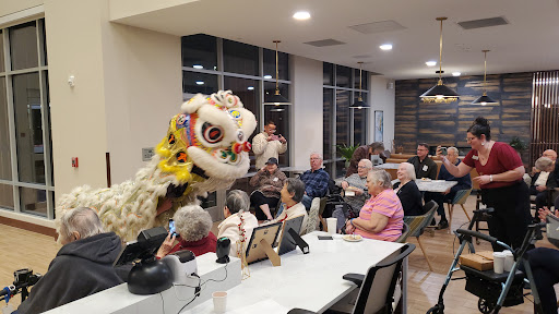 A vibrant lion dance performance captivates a group of seniors during a community gathering.