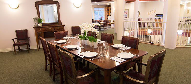 A well-appointed dining room with a large table set for dinner, featuring an orchid centerpiece.