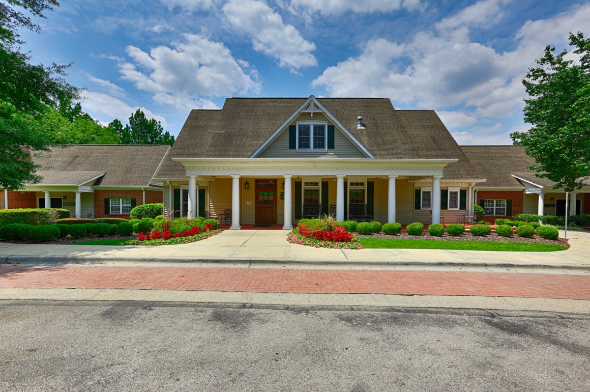 A beautiful house with a well-maintained front yard under a partly cloudy sky.