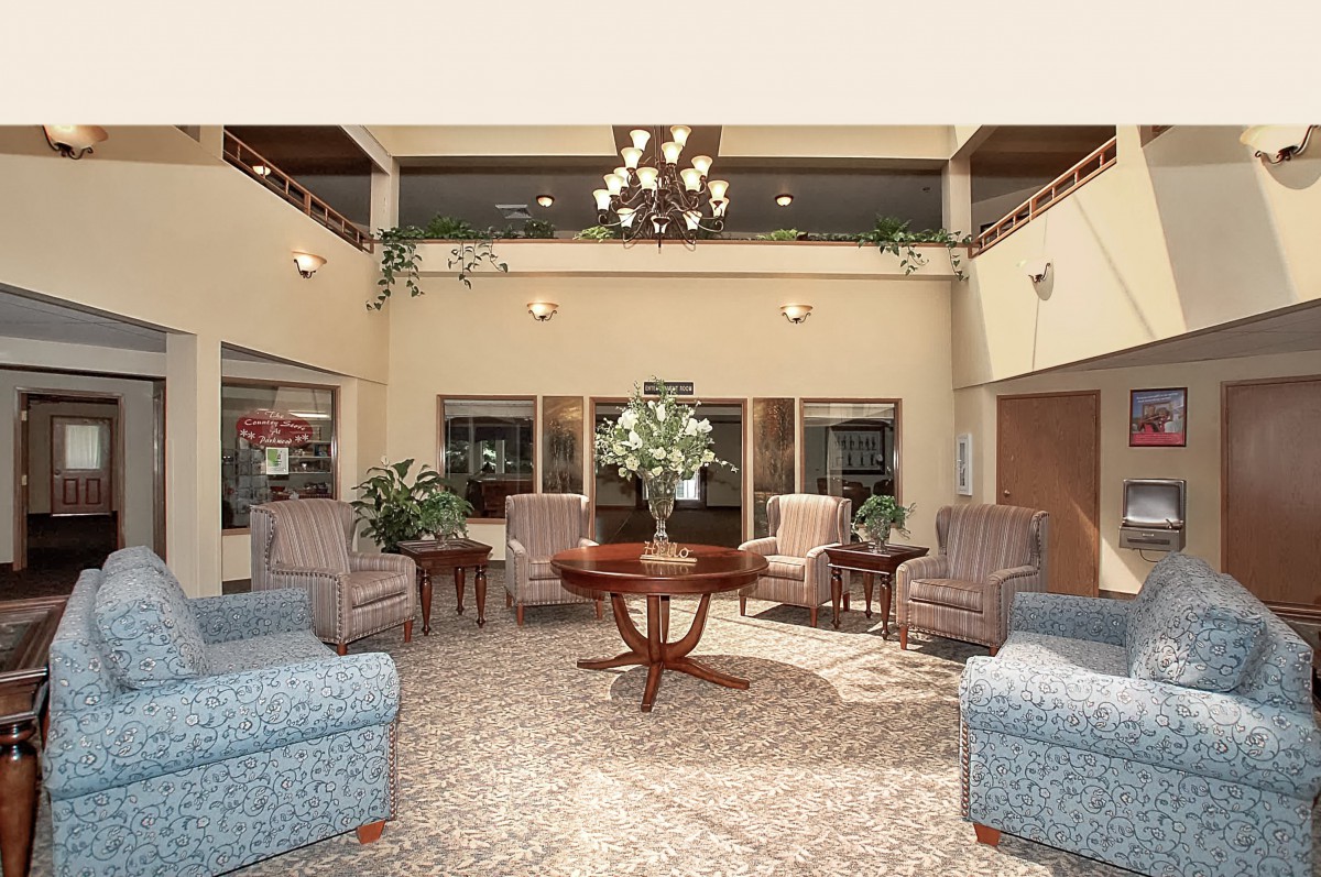 A well-furnished lobby featuring a chandelier, comfortable seating with armchairs, and a central table adorned with flowers.