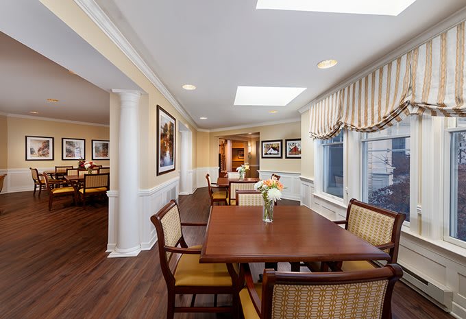 A well-appointed dining room featuring a wooden table and chairs, accented by large windows with striped curtains and warm lighting.