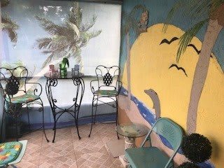 A cozy outdoor area with a tropical mural and wrought iron furniture.
