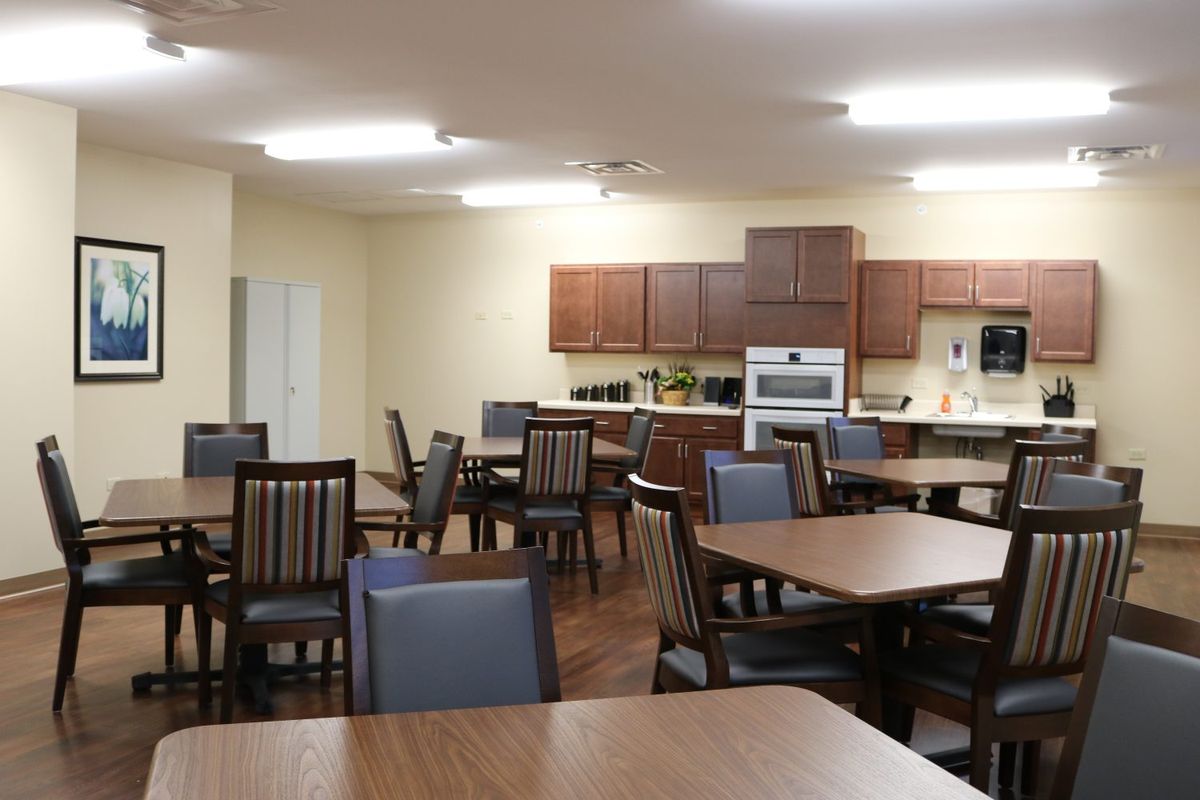 A communal kitchen and dining area with tables, chairs, and appliances.