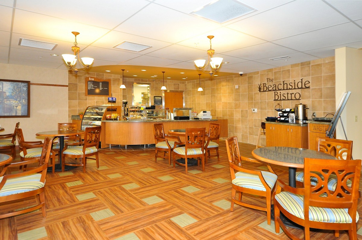A cozy cafe interior with wooden flooring, seating area, and a counter.