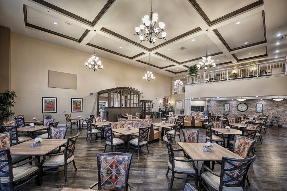 A spacious restaurant interior featuring elegant chandeliers and neatly arranged tables.