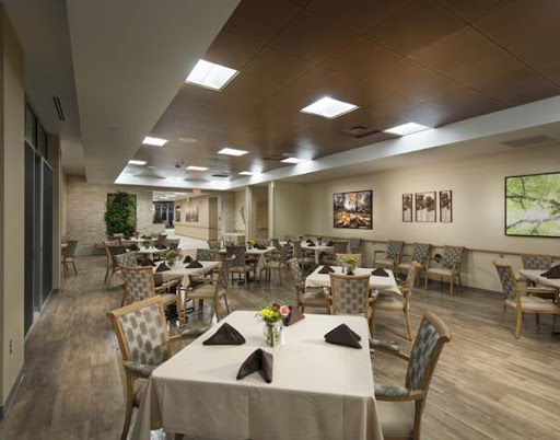 A spacious and elegantly designed restaurant dining area, featuring neatly arranged tables with floral centerpieces.