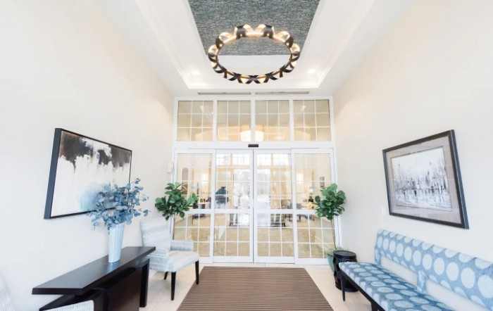 A well-lit lobby entrance with a chandelier, seating, and decorative plants.