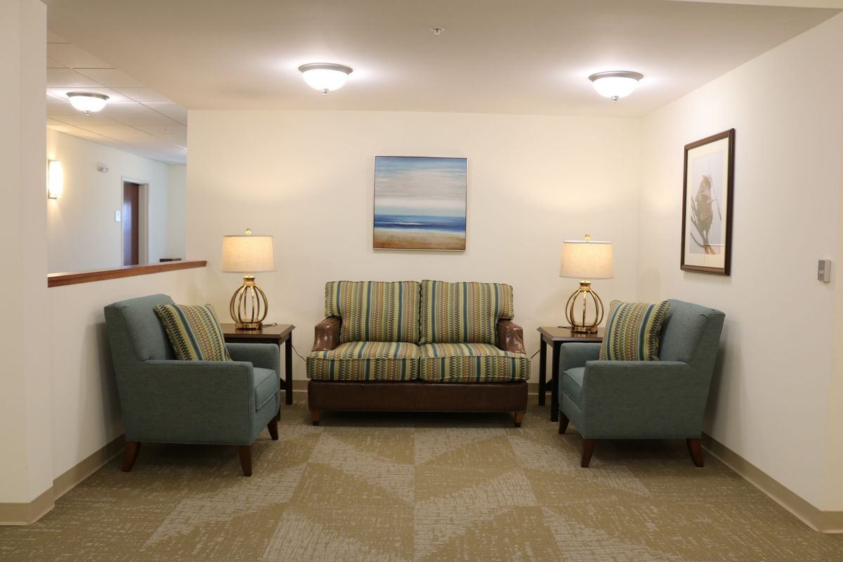A cozy living room with a sofa, two armchairs, decorative lamps, and a painting on the wall.