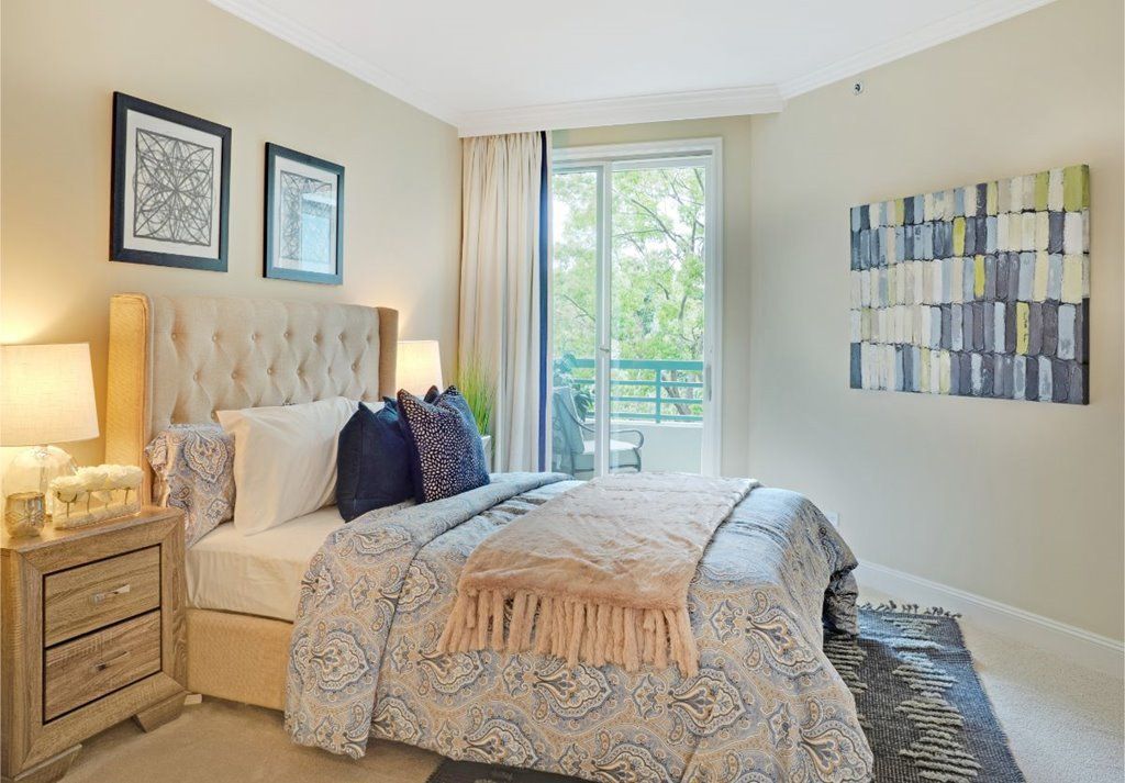 A well-decorated bedroom with a comfortable bed, elegant decor, and natural light from a large window.