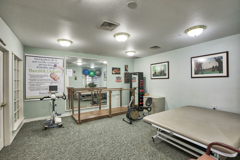 A rehabilitation gym with exercise equipment, including bicycles and a spacious interior.