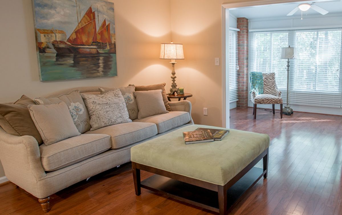 A cozy living room featuring a comfortable sofa, a lamp on a side table, and a large ottoman in the center.