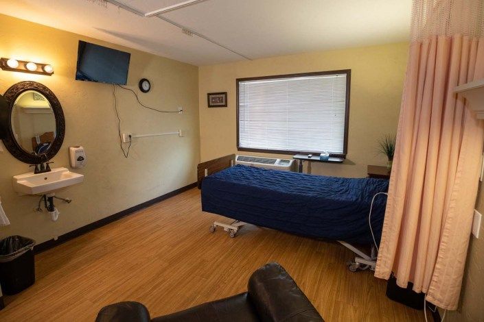A hospital room with a bed, television, and medical equipment.