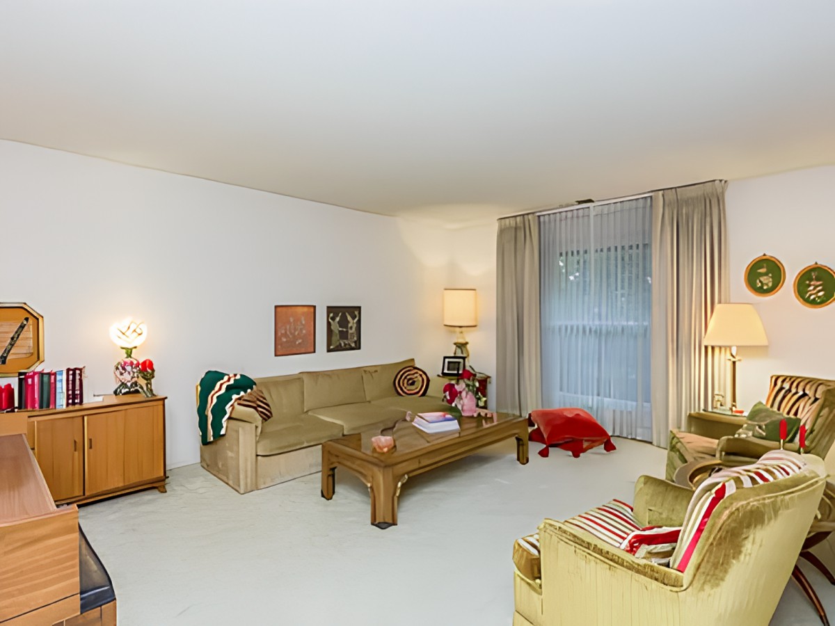 A cozy living room with vintage decor, featuring a sofa, coffee table, and armchairs.