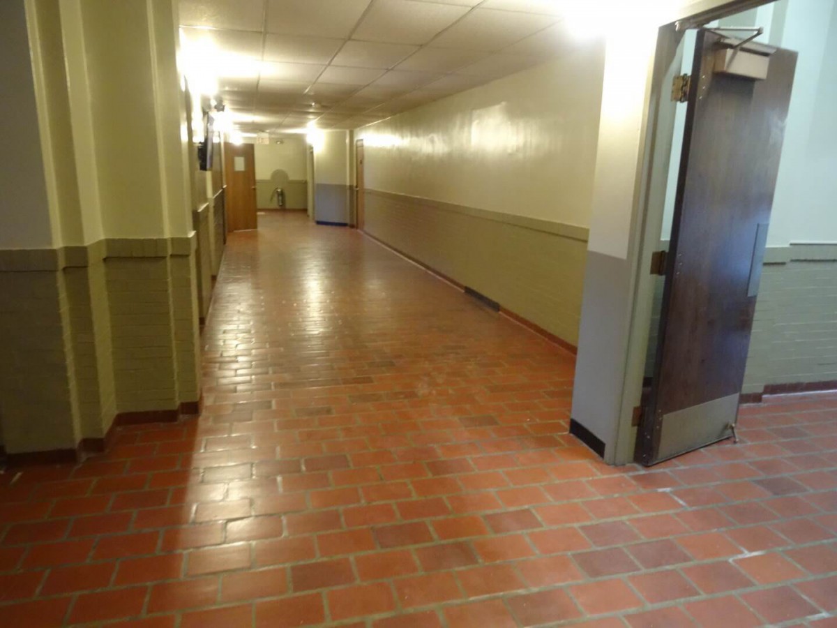 An empty hallway with a brick floor and warm lighting.