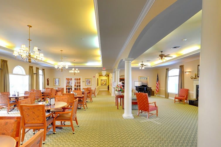 A spacious dining area with multiple tables and chairs, featuring warm lighting and elegant interior design.