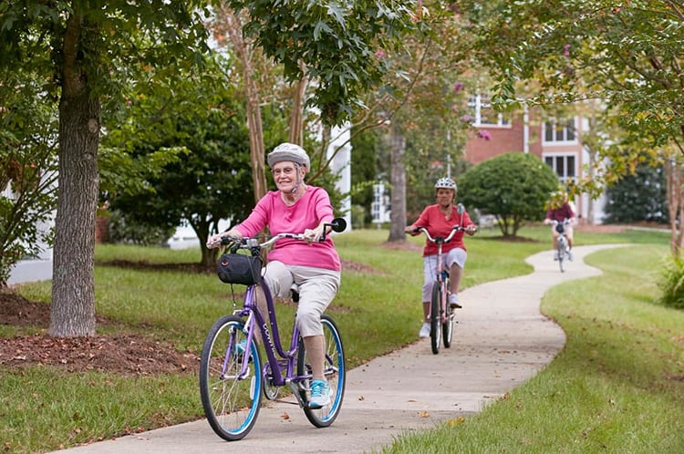 Seniors enjoying a bike ride on a park path.