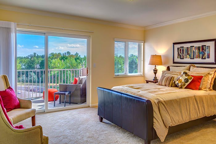 A cozy bedroom with a balcony offering a scenic view.