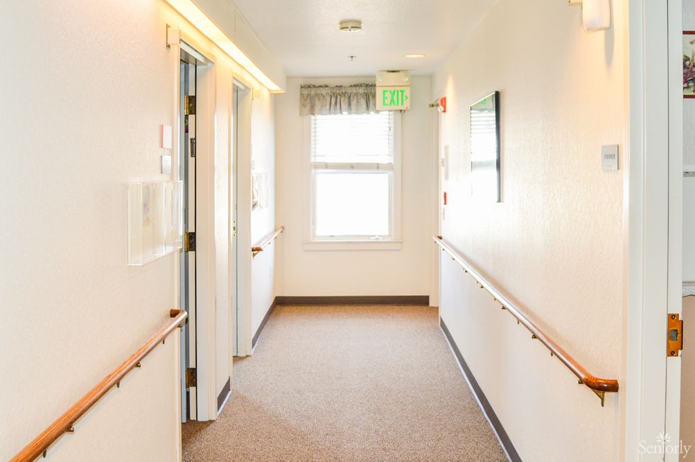 A brightly lit hallway with multiple doors and a window at the end.