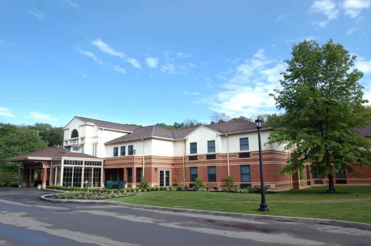 A modern brick building surrounded by greenery under a clear blue sky.