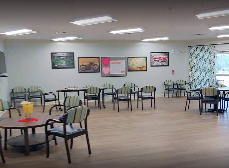 A spacious and well-lit waiting area with chairs and tables, adorned with artwork on the walls.