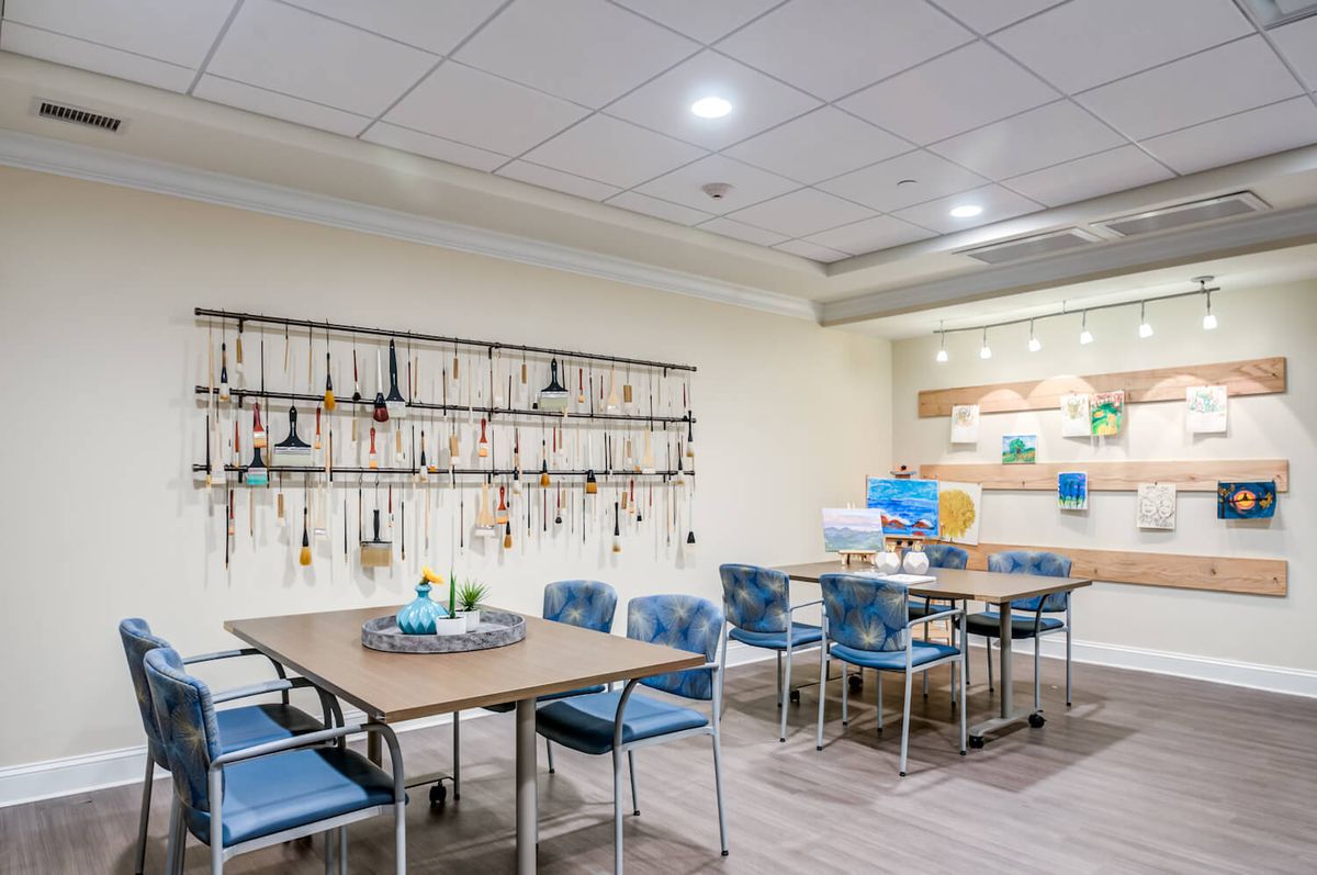 A well-lit meeting room with tables and chairs, featuring decorative elements on the wall.