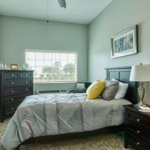 A cozy bedroom with a neatly made bed, pillows, and dark wood furniture.