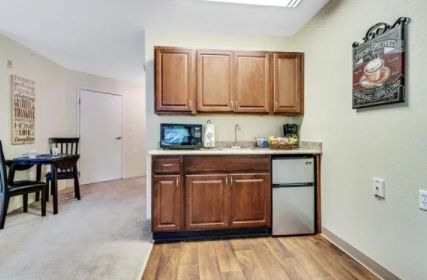 A compact kitchenette featuring wooden cabinets, a microwave, and a small refrigerator.