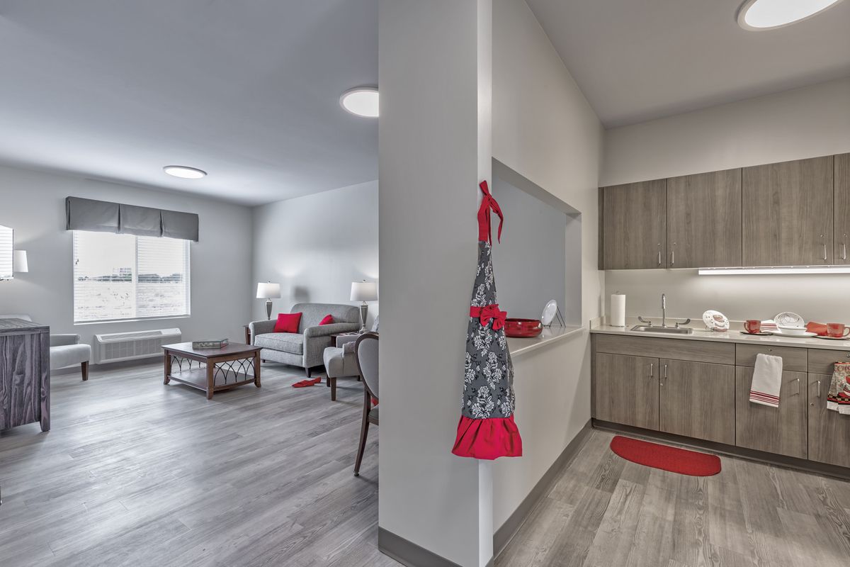A modern open-plan living room and kitchen with stylish decor, featuring neutral tones and red accents.