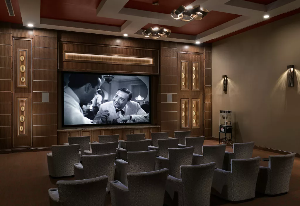 A luxurious home theater with comfortable seating and a black-and-white movie playing on the projector screen.