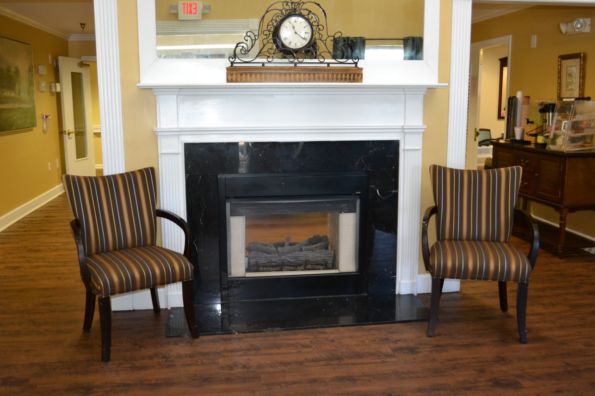 A cozy fireplace flanked by two striped chairs in a warmly decorated living space.