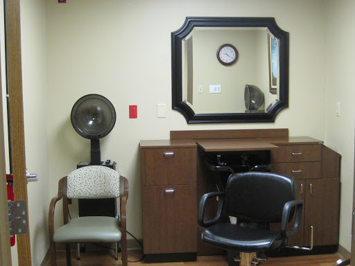 A cozy interior of a salon's waiting area featuring a mirror, clock, and comfortable chairs.