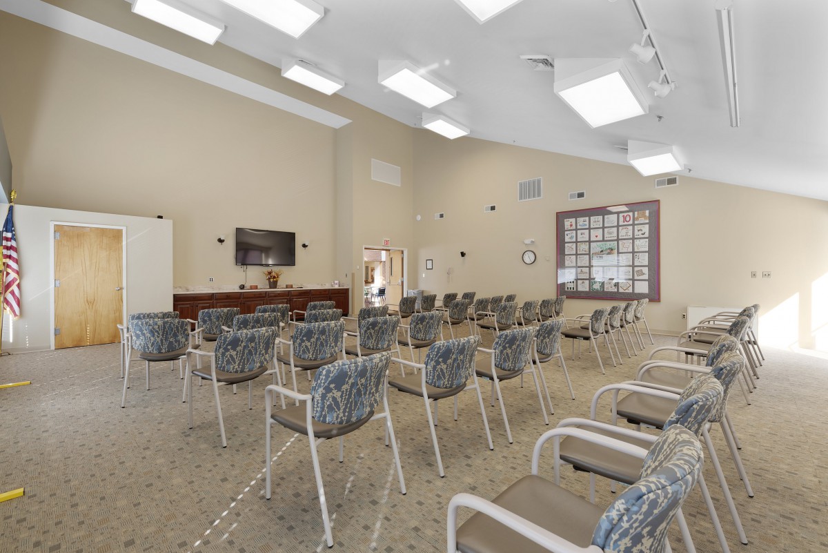An empty conference room with neatly arranged chairs and a television at the front.