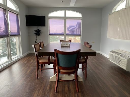 A modern dining room featuring a large table, chairs, and a view through expansive windows.